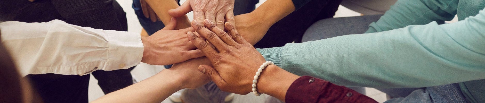 hands of various people placed together in a huddle