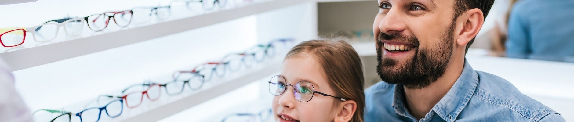 Father picking out glasses with daughter wearing glasses