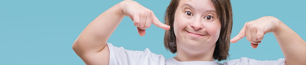 Young adult woman with Down syndrome smiles confidently.