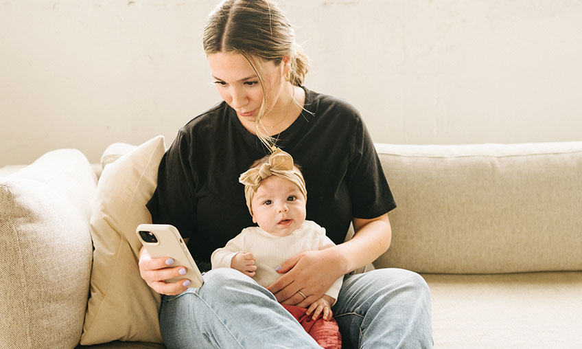 mom texting on phone with baby in lap