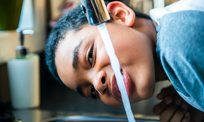 boy drinking from kitchen faucet