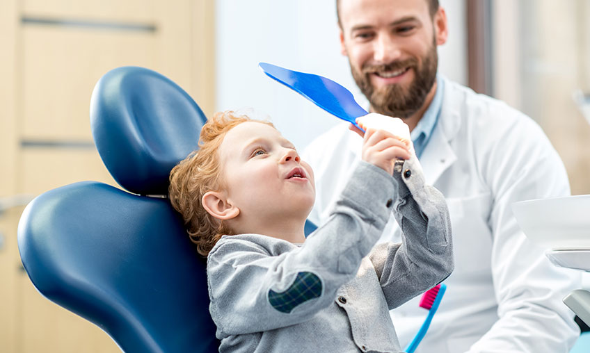 child checking out mouth at dentist appointment