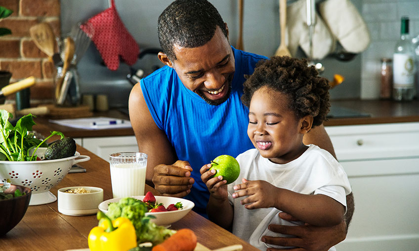 dad giving young son healthy food