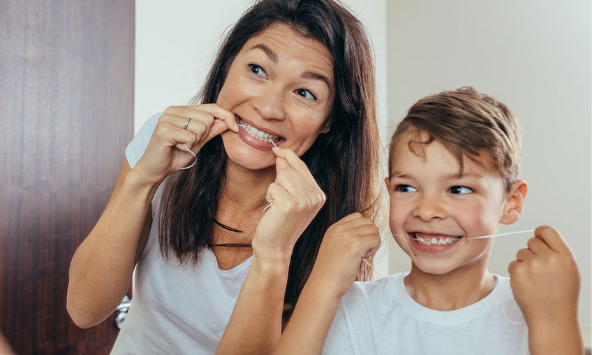 mom and son flossing in bathroom mirror