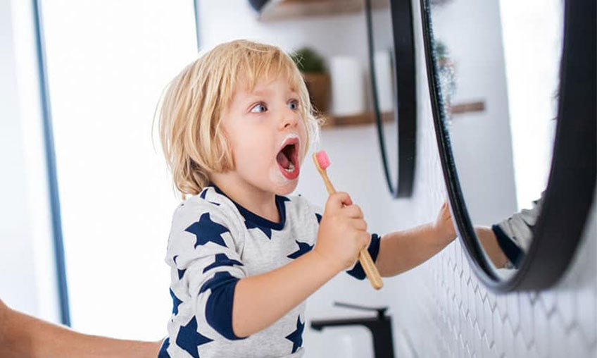 child brushing teeth near mirror