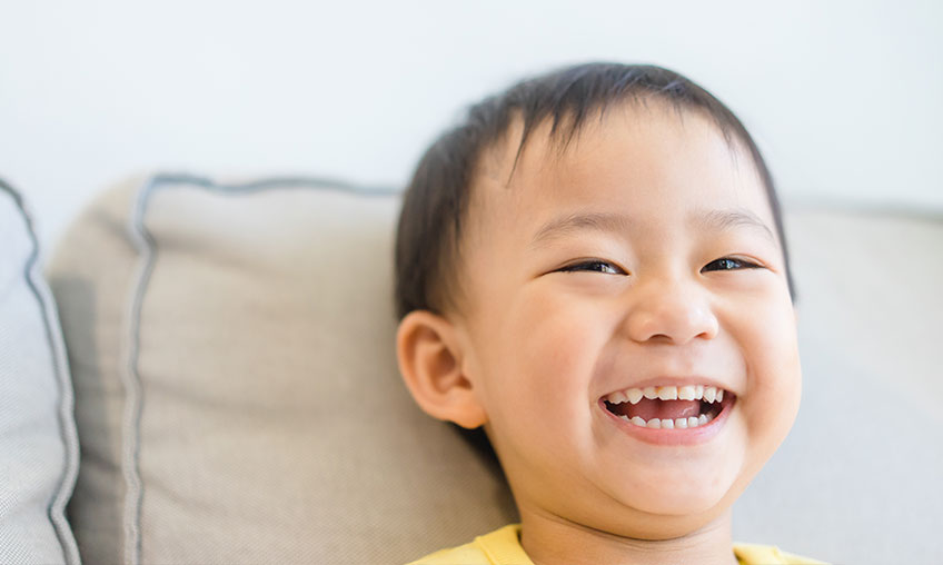 Infante asiático niño sonriendo y mostrando los dientes