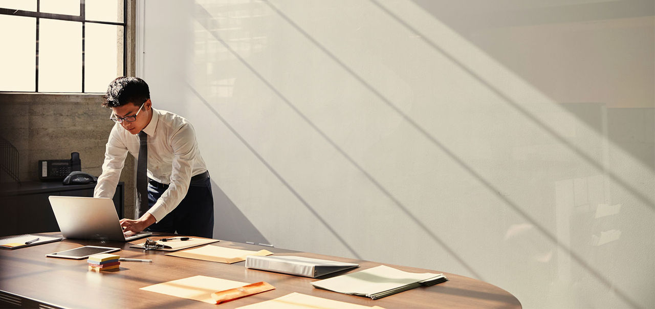 man standing at desk using a laptop