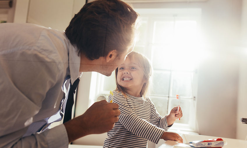 dad checking child's teeth while brushing